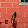 person in brown leather jacket standing in front of brown brick wall